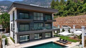 Exterior view of the three-story 5 Star Infinity Holiday Villa in Alanya, showing the modern slate-grey architecture, private pool, and hillside garden.
