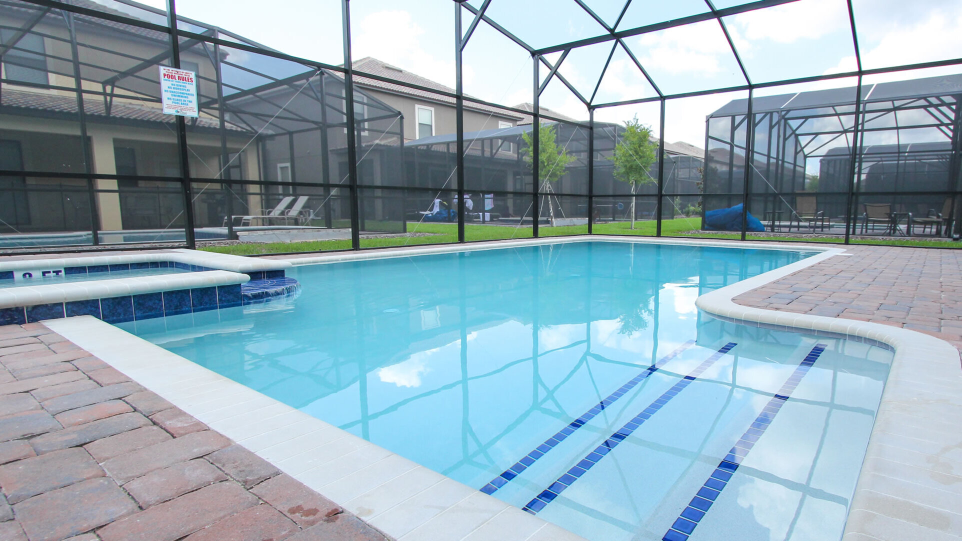  A bright private swimming pool and integrated spa inside a screened-in lanai at a ChampionsGate Resort villa, with neighboring homes visible in the background.