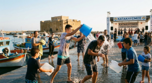 Cypriots celebrating the ancient Kataklysmos water festival along Paphos Harbour, backdropped by the medieval castle.