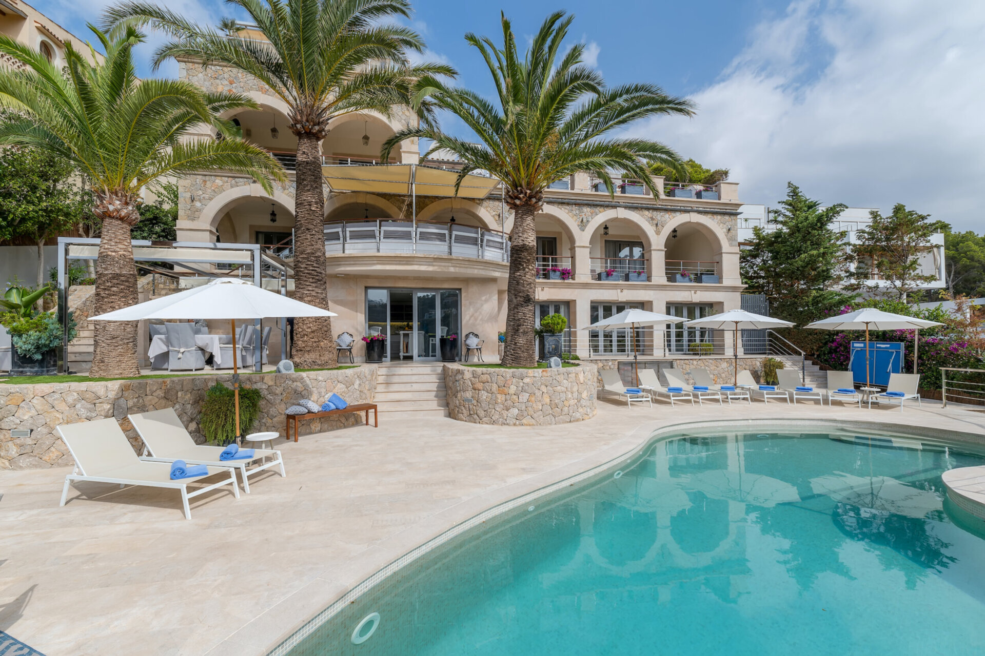 Front-on view of a multi-level luxury stone villa in Mallorca, showing spacious terraces and outdoor dining areas designed for large fam
                 width=