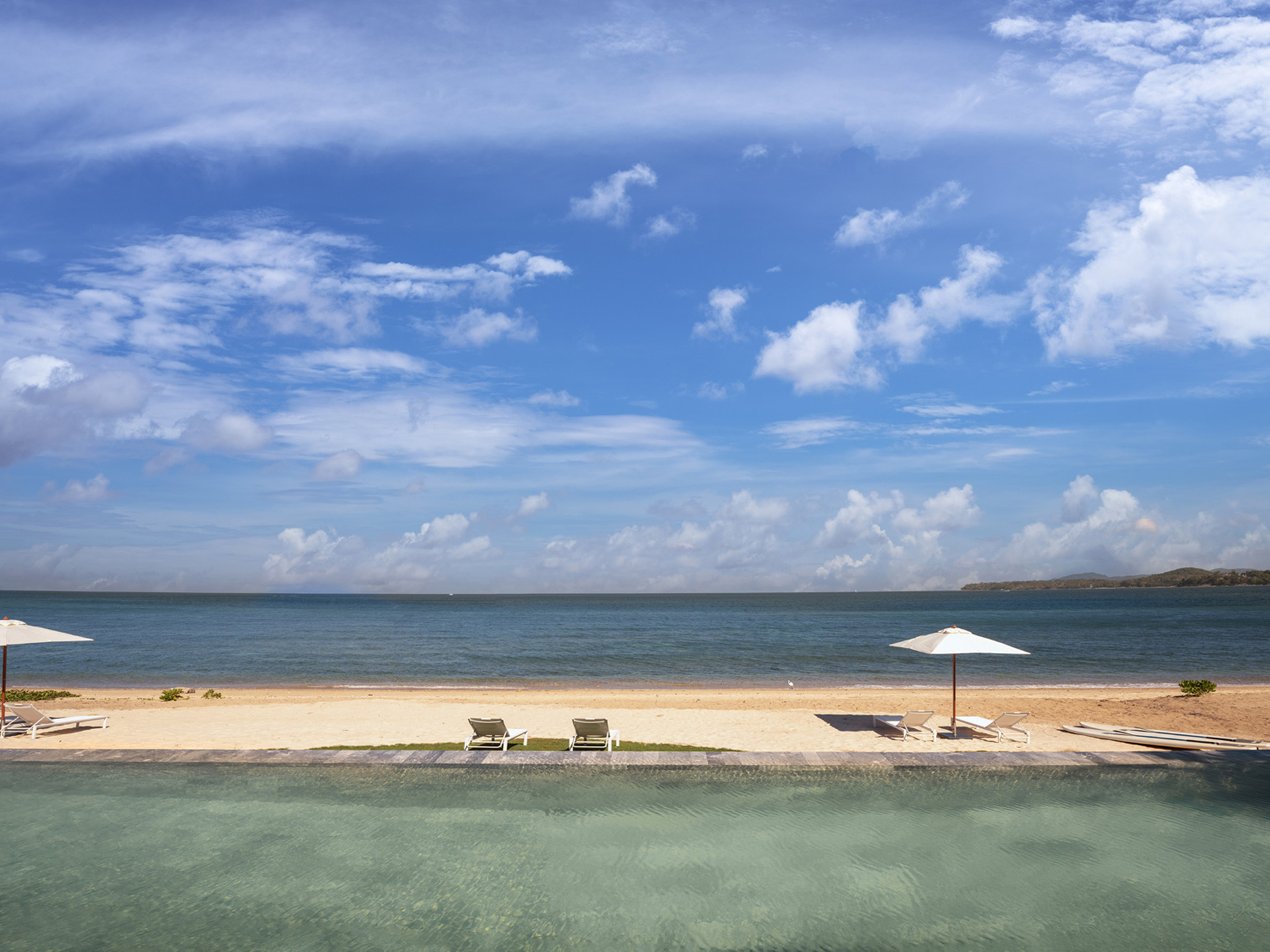 Beachfront villa pool overlooking a calm Phuket beach during dry season